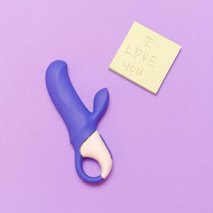 A purple silicone vibrator next to a sticky note saying 'I love you' on a lavender surface.